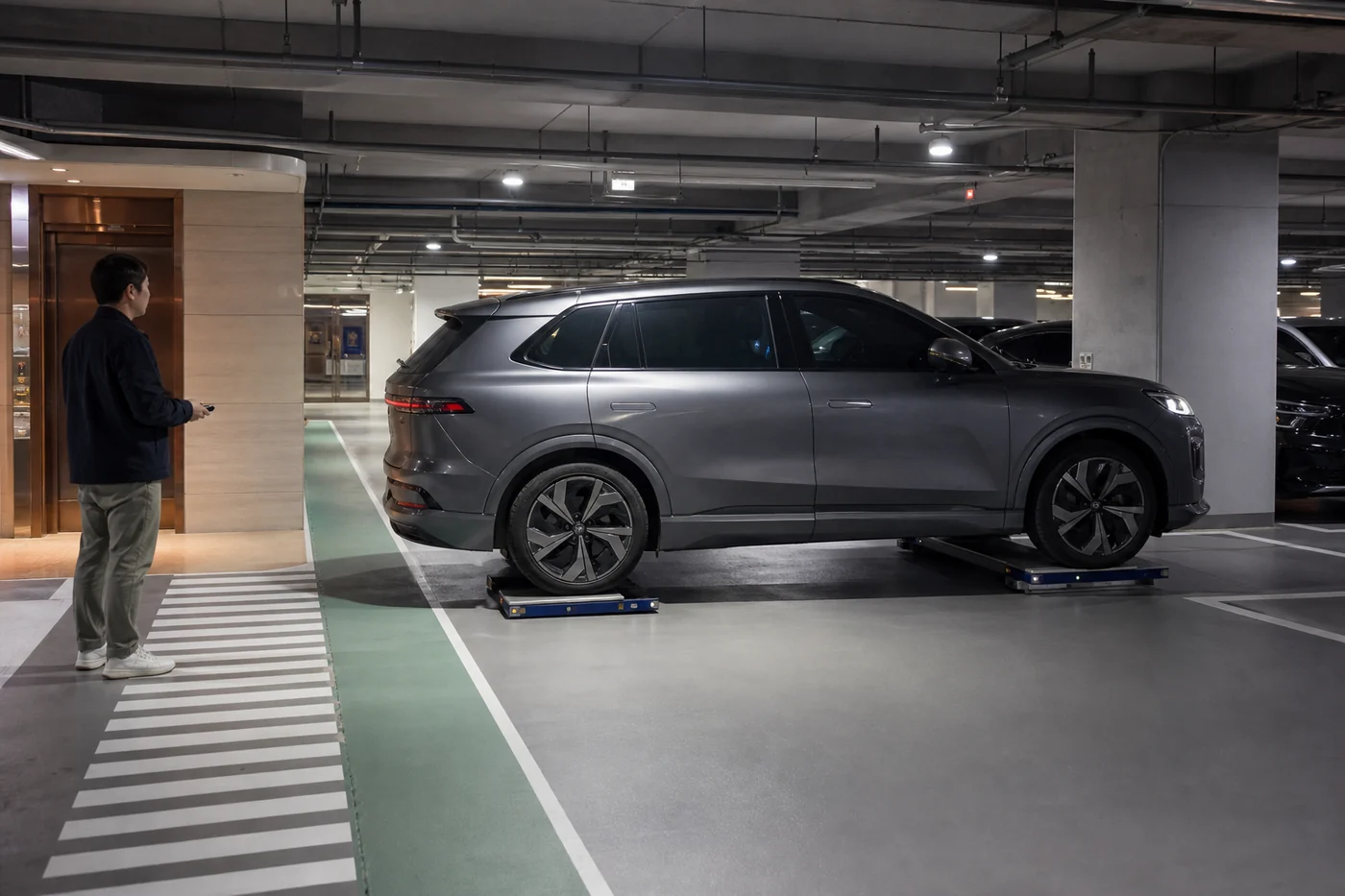 Two low-profile parking robots lift a dark silver SUV in an underground apartment garage while a resident waits near the elevator.
